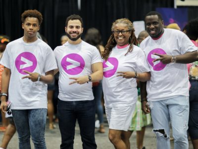 Group of four people at the Greater Than HIV booth at #ESSENCEFEST wearing branded t-shirts